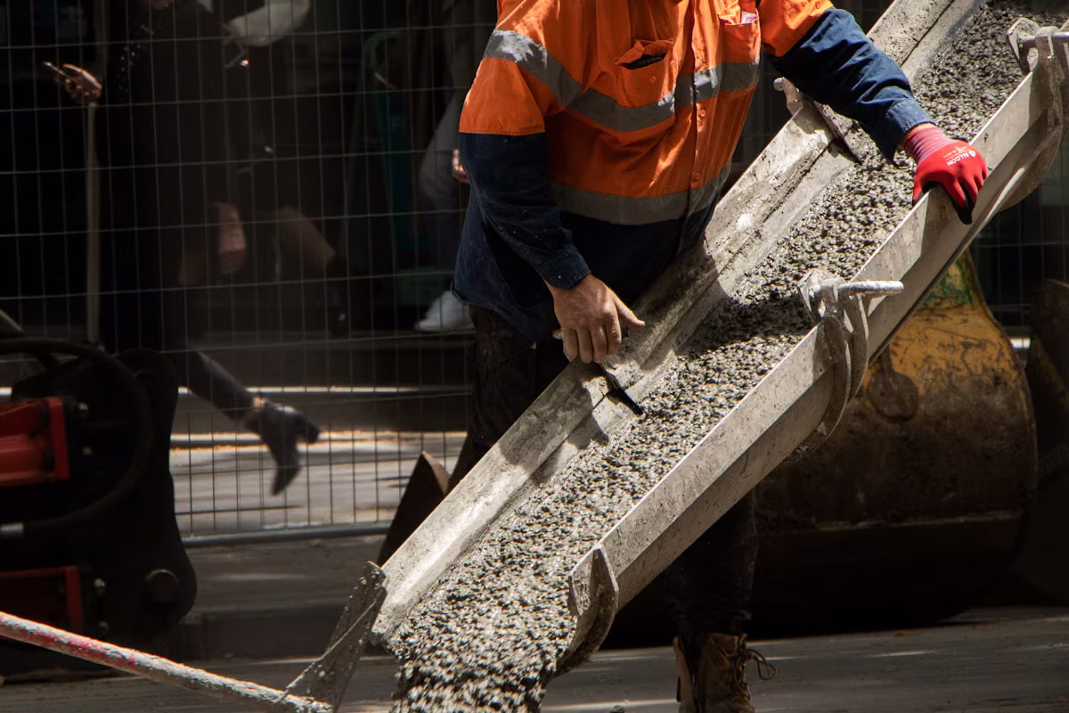A worker pouring and finishing wet concrete