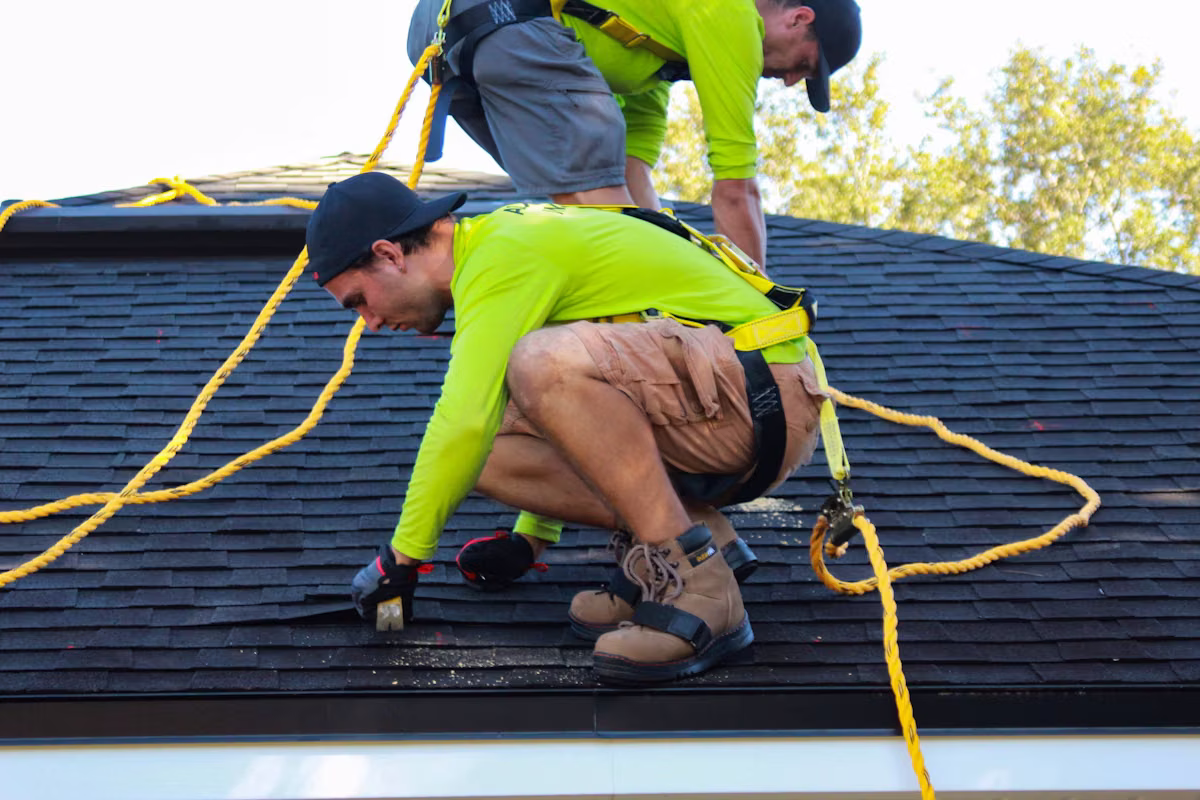 Two roofers working on the roof of a house